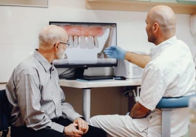 Il dentista spiega i rischi e le controindicazione degli impianti dentali a un paziente